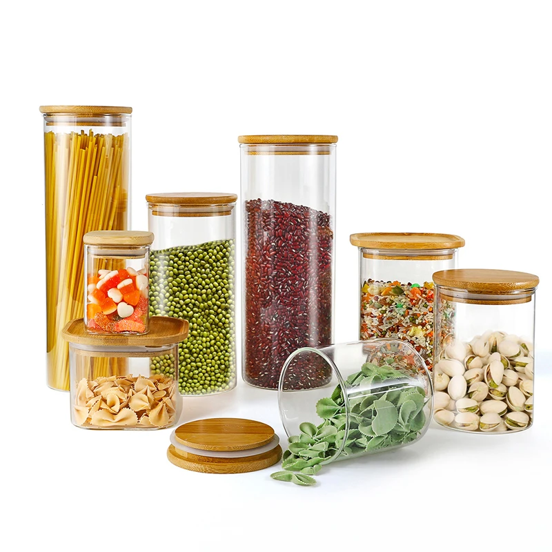 Clear cylindrical pantry jars with bamboo-style lids holding dry ingredients