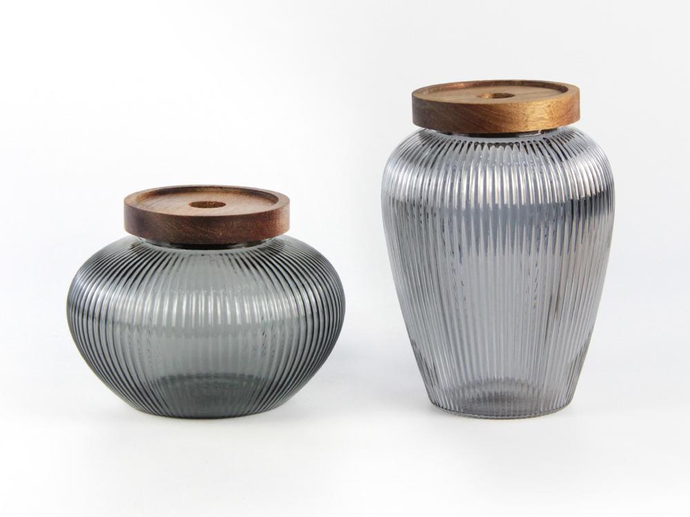 Low and tall grey-toned fluted glass storage forms with wooden-looking lids